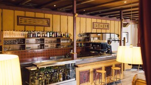 A bar area with shelves of bottles, glasses, and stools.