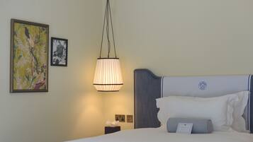 A hotel room with a bed, a nightstand, a lamp, and two framed pictures on the wall.