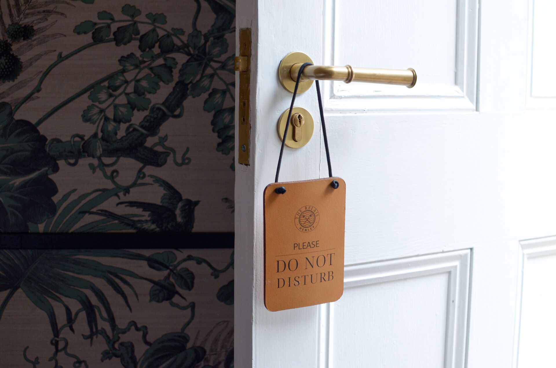 A door with a brass handle and a 'Please Do Not Disturb' sign.