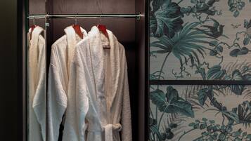 A closet with three white robes hanging on a metal rod.