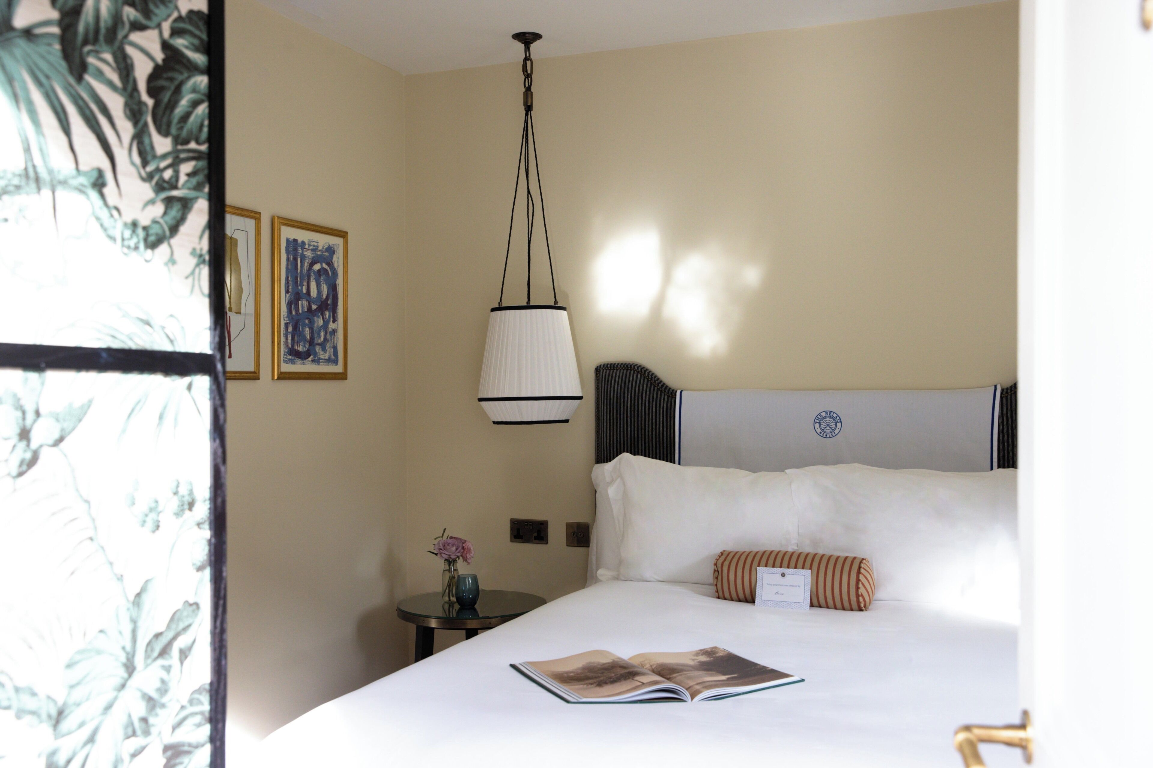Ein Hotelzimmer mit einem Bett, einem Nachttisch, einer Lampe und einem gerahmten Bild an der Wand.