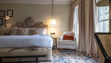 A hotel room with a large bed, a bedside table, a chair, and a patterned carpet.