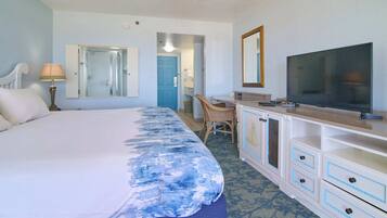 Habitación de hotel con cama, escritorio, televisor y espejo.