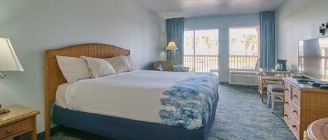 Ein Hotelzimmer mit Bett, Schreibtisch, Stuhl, Lampe und Blick ins Freie.