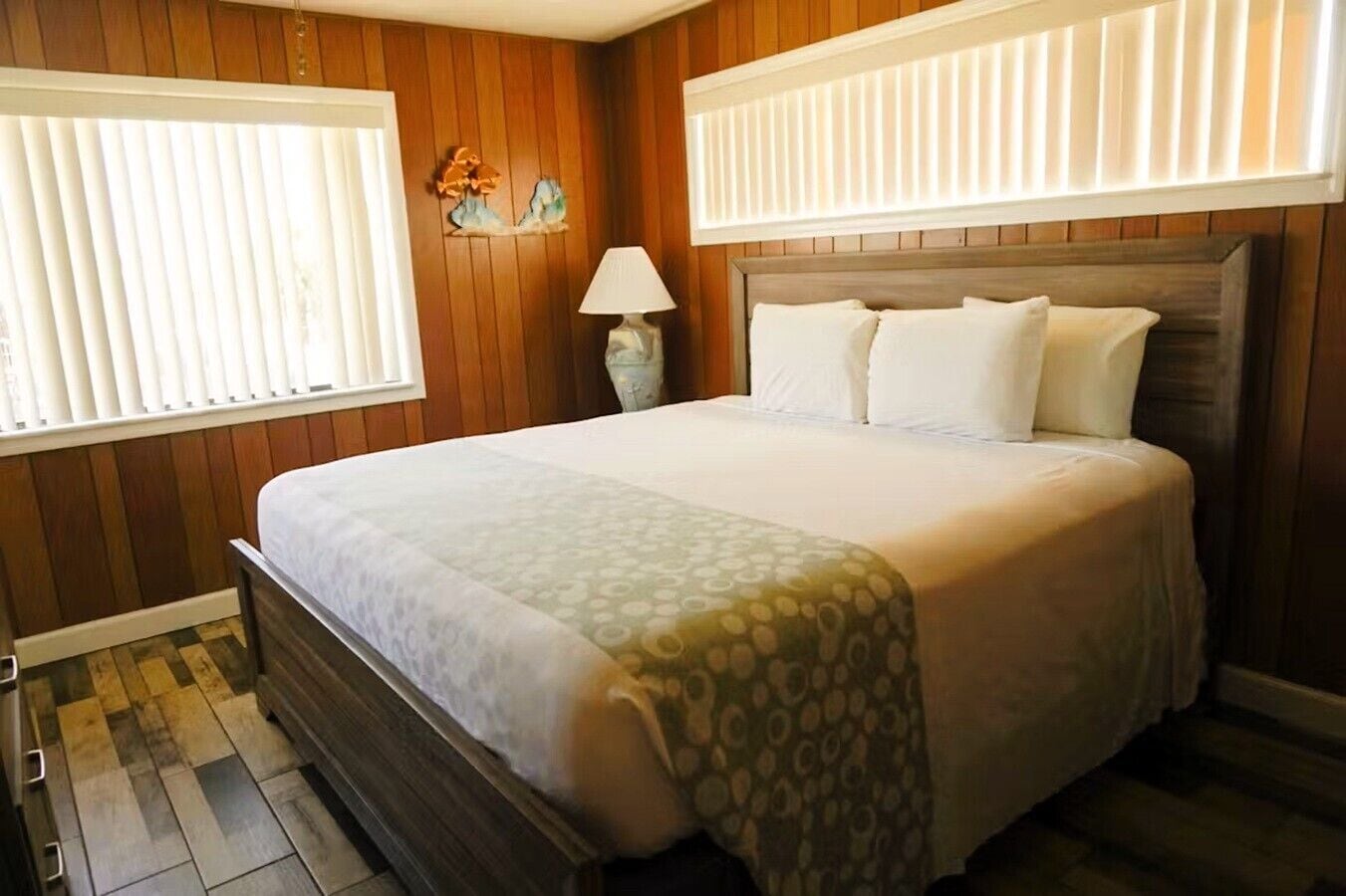 Une chambre à coucher bien aménagée, avec un grand lit, des murs lambrissés, une lampe de chevet et un objet décoratif placé au-dessus du lit.