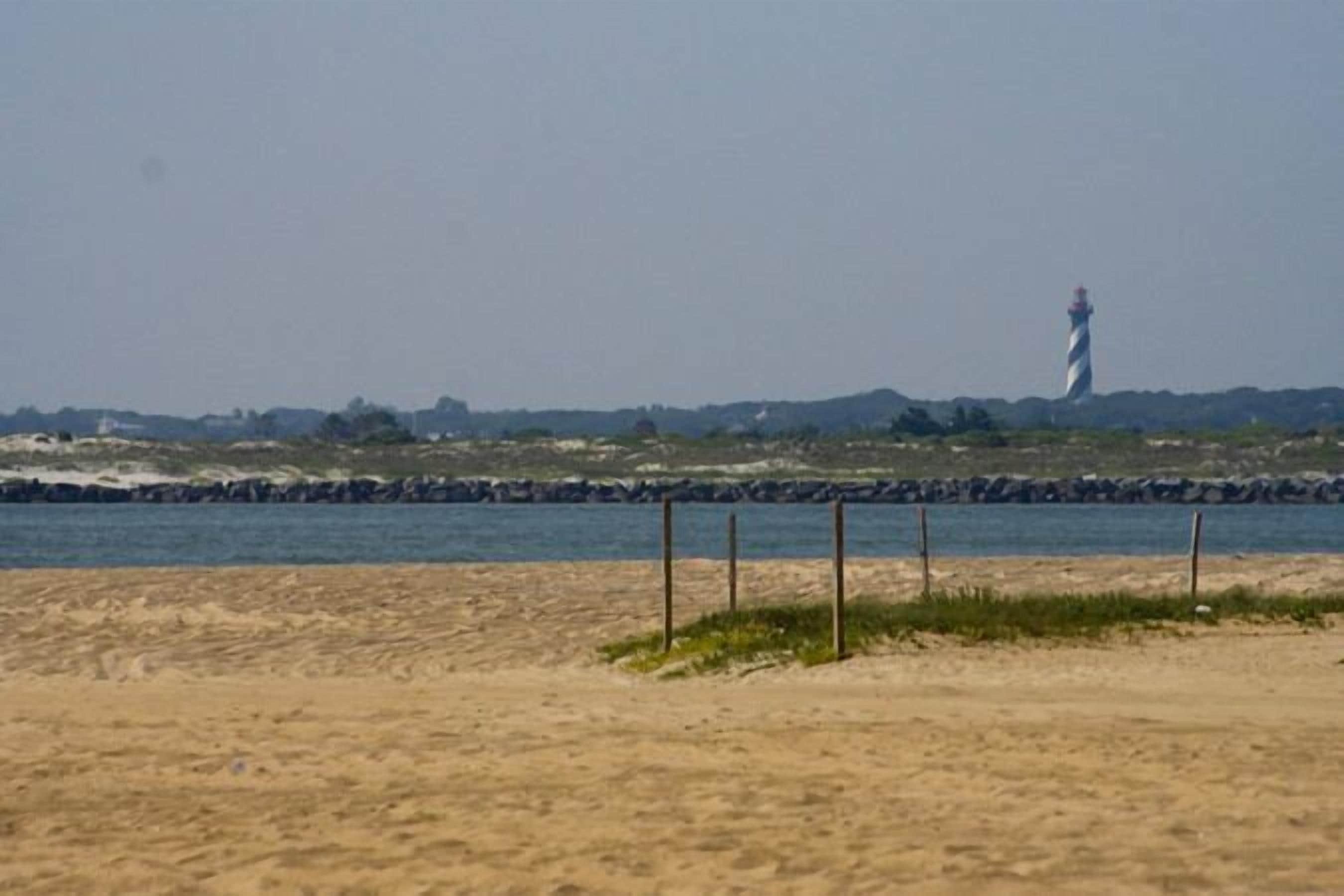 A beach with a lighthouse in the distance.