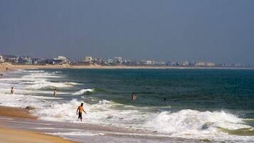 A beach with waves and people swimming.