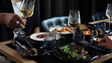 Una mesa de comedor con varios platos y copas de vino, ubicada en una sala con poca luz y una silla de cuero negro al fondo.