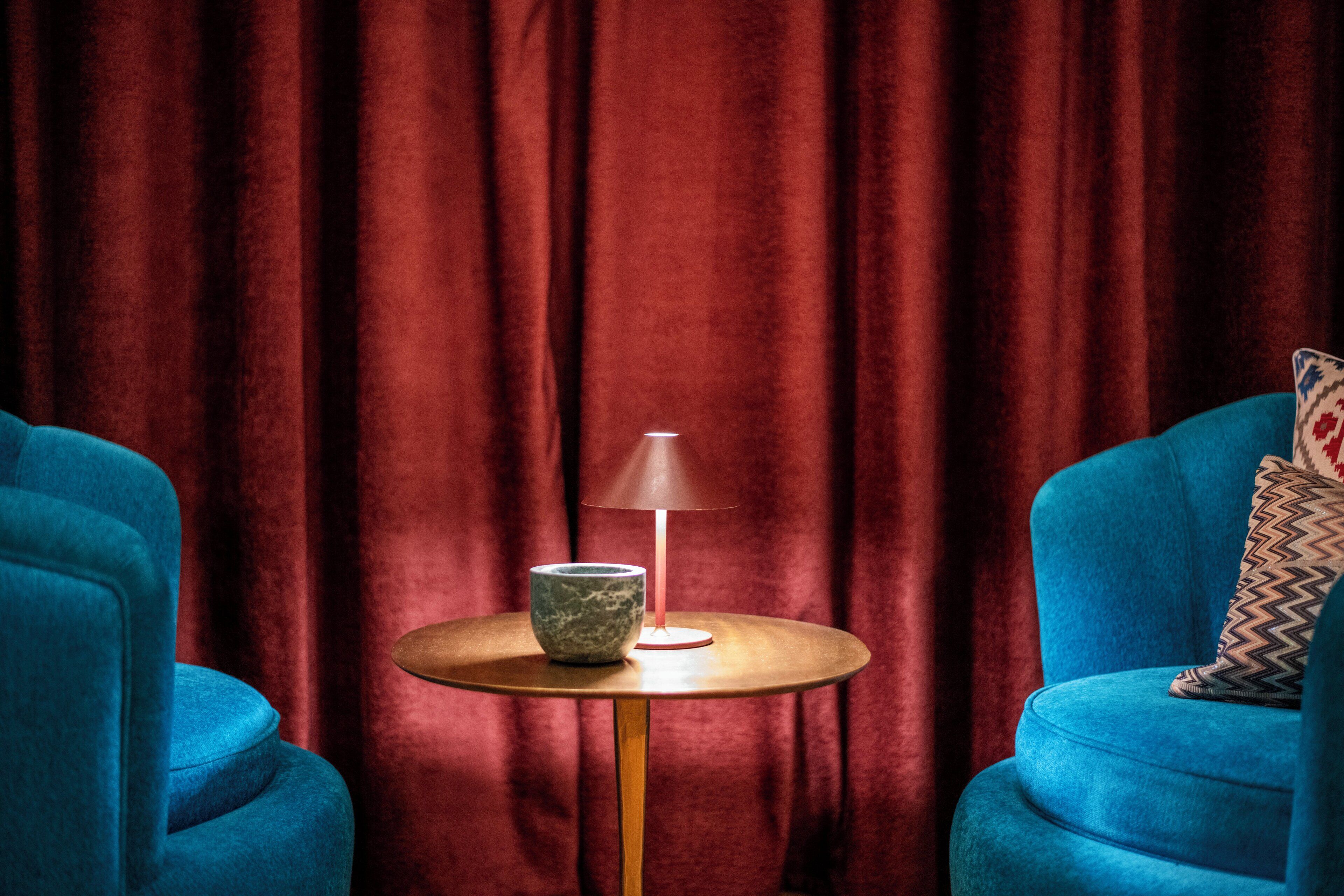 A room with a round table, a lamp, and two blue armchairs.