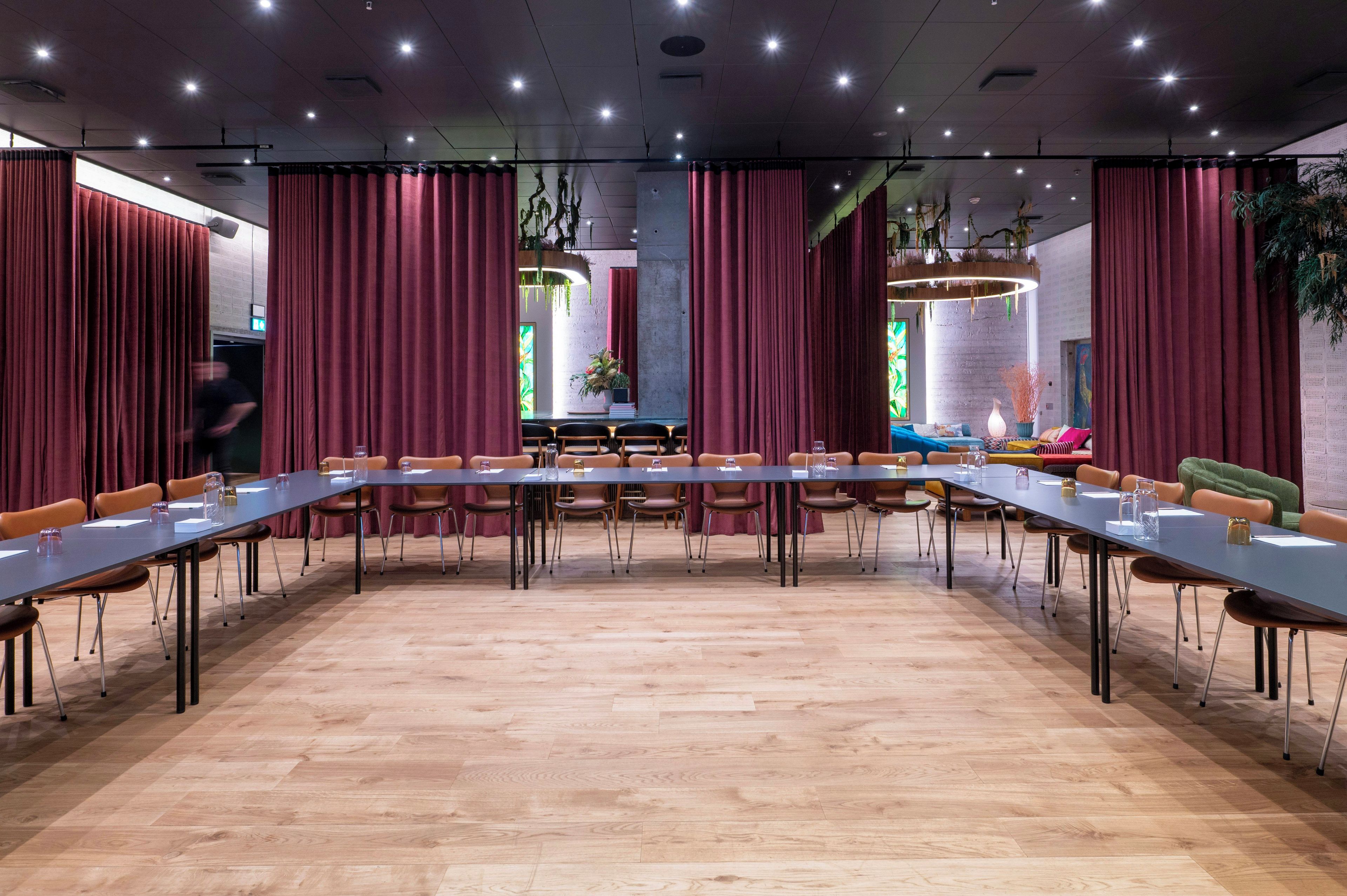 A conference room with a long table, chairs, and curtains.