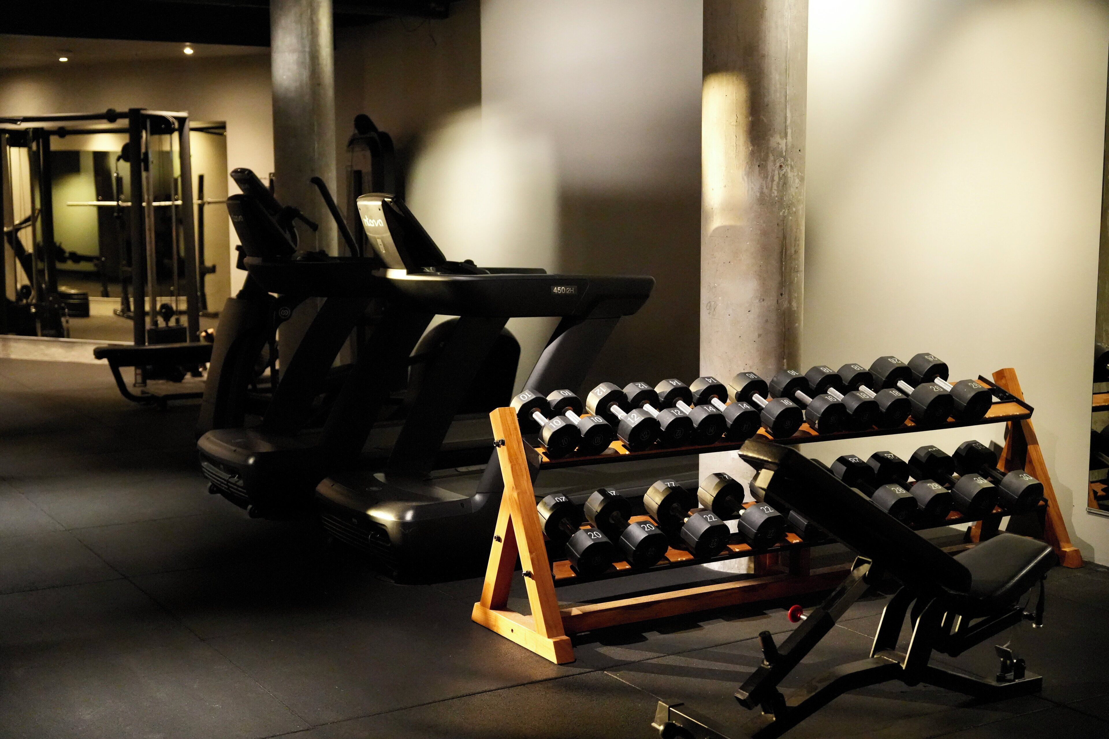 Ein Fitnessstudio mit Laufbändern, Kurzhanteln und Krafttrainingsgeräten.