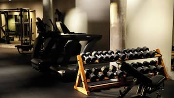 Un gimnasio con cintas de correr, pesas y máquinas de musculación.