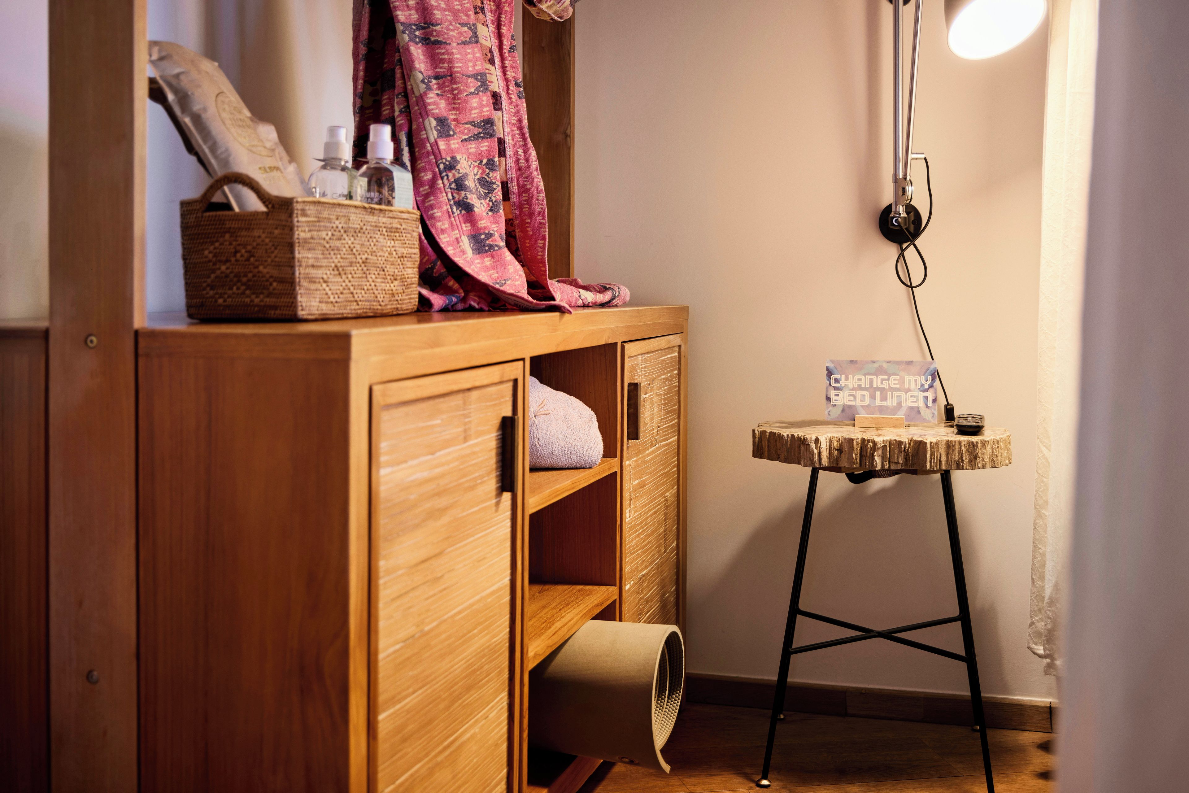 A wooden cabinet with shelves, a small table with a sign, and a lamp.