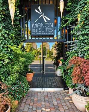The entrance to a hotel with a sign reading 'MANON les SUITES GULDSMEDEN HOTELS'.