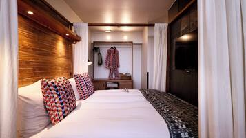 Una habitación de hotel con una cama grande, un armario, un espejo y un televisor.