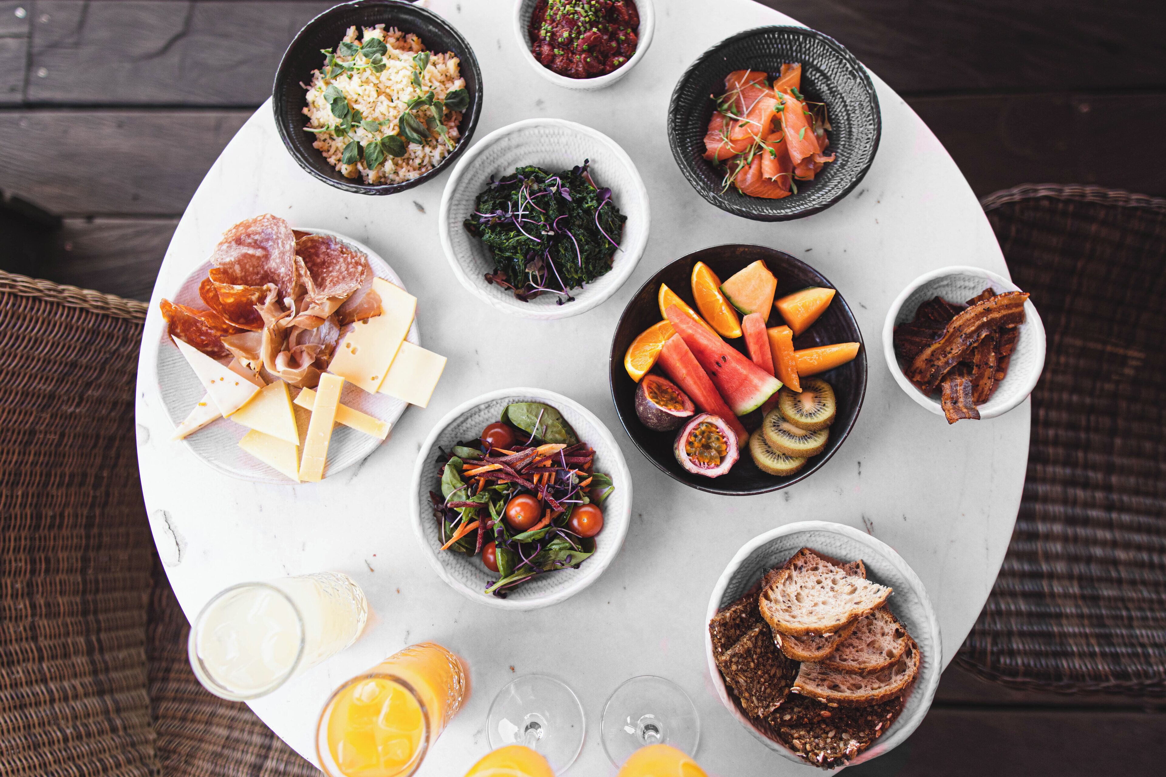A round table with various dishes including salads, fruits, and bread.