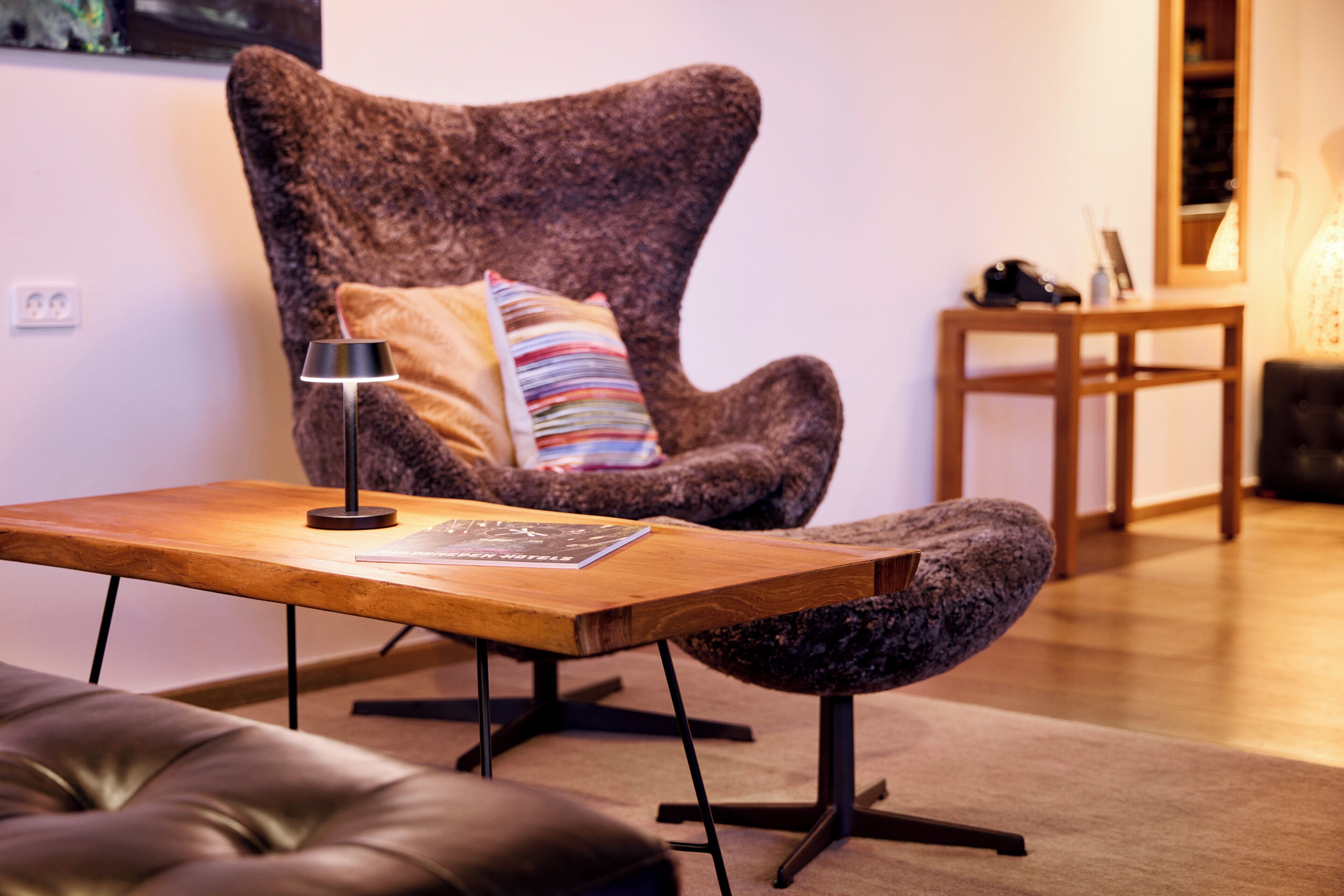 Un salon confortable avec un fauteuil moelleux, une petite table en bois et une lampe.
