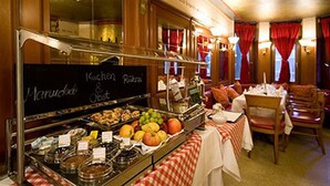 Een buffetruimte met diverse gerechten, een krijtbordmenu en een zithoek met tafels en stoelen.