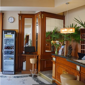 A hotel lobby with a Coca-Cola vending machine, a desk with a computer, a mirror, and a reception area with a plant and a lamp. - Albergo City Hotel Berlin (Berlin)