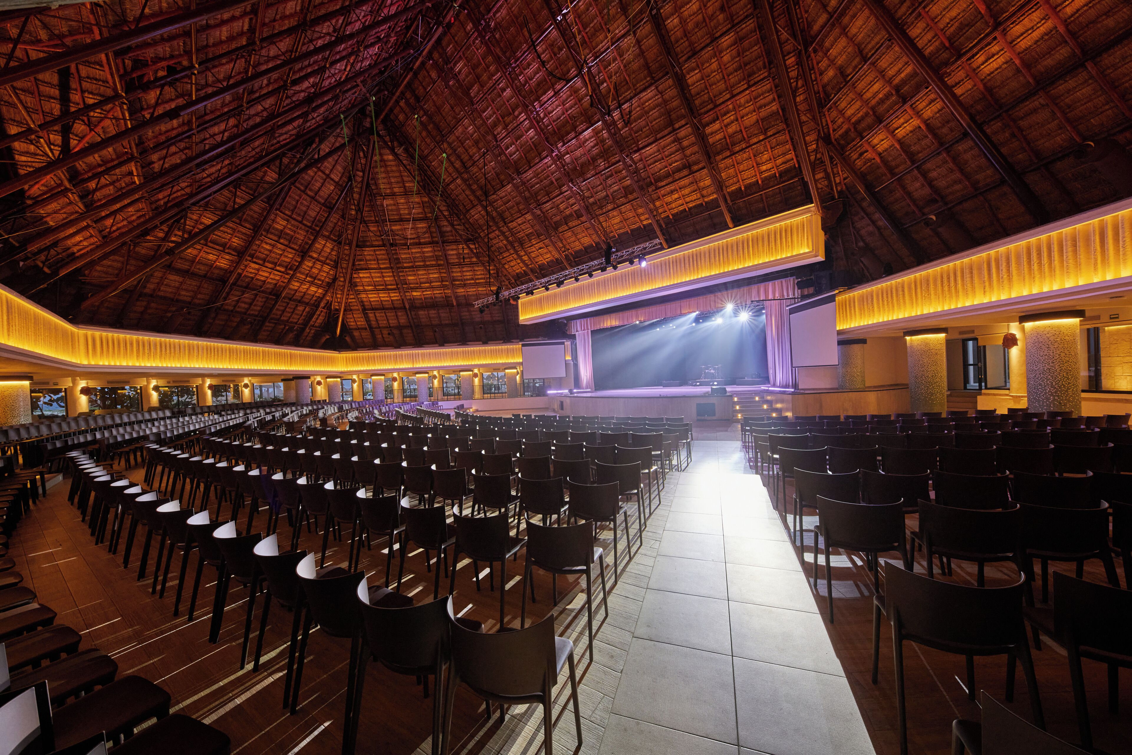 A large indoor venue with rows of chairs, a stage, and a high ceiling.