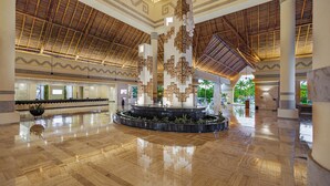 A spacious lobby with a high ceiling, a central fountain, and a polished floor.