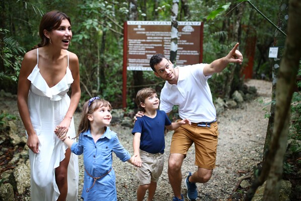 A family walking on a forest trail with a signboard in the background.