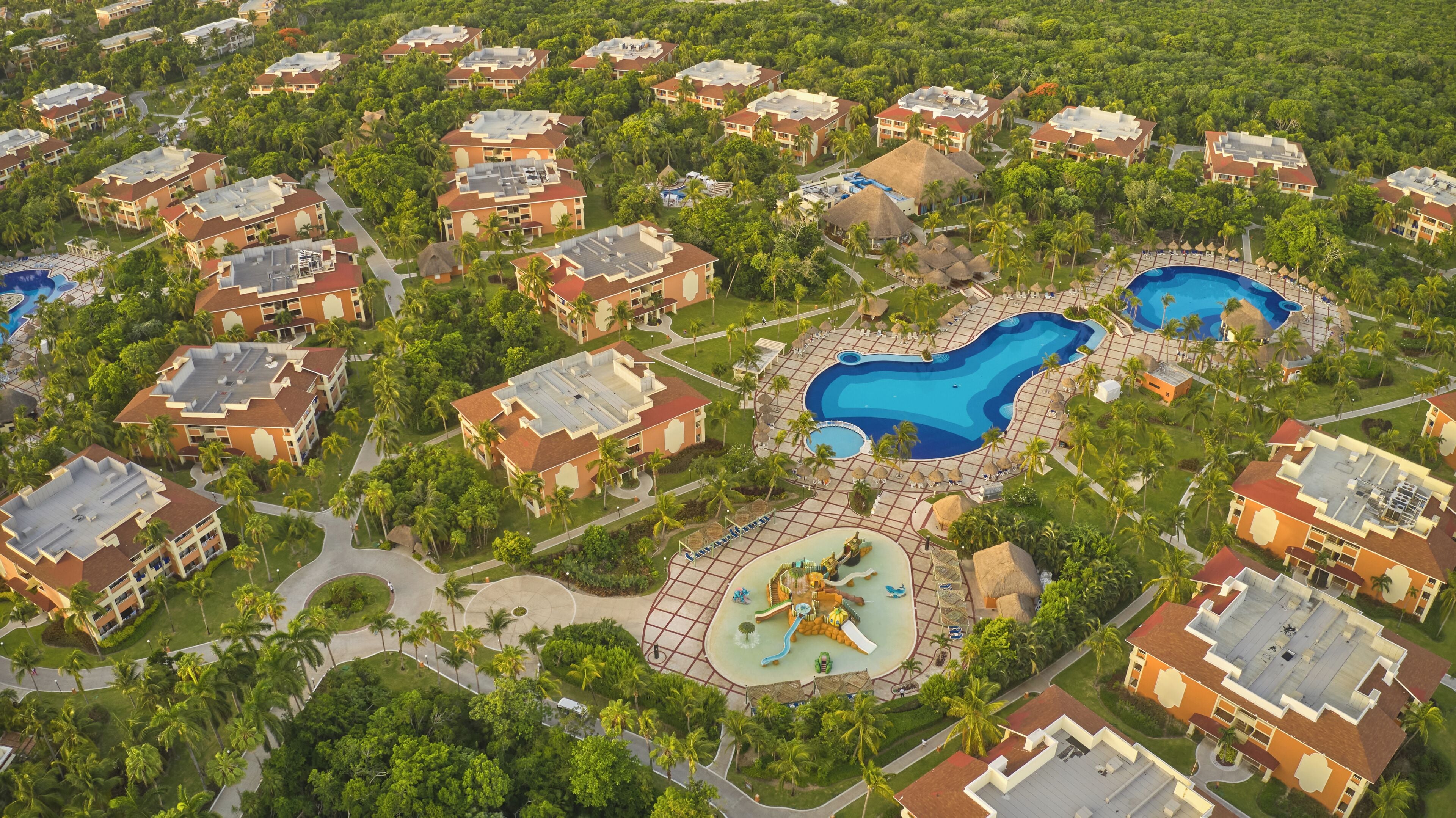 An aerial view of a resort with multiple buildings, a central pool area, and a water park.