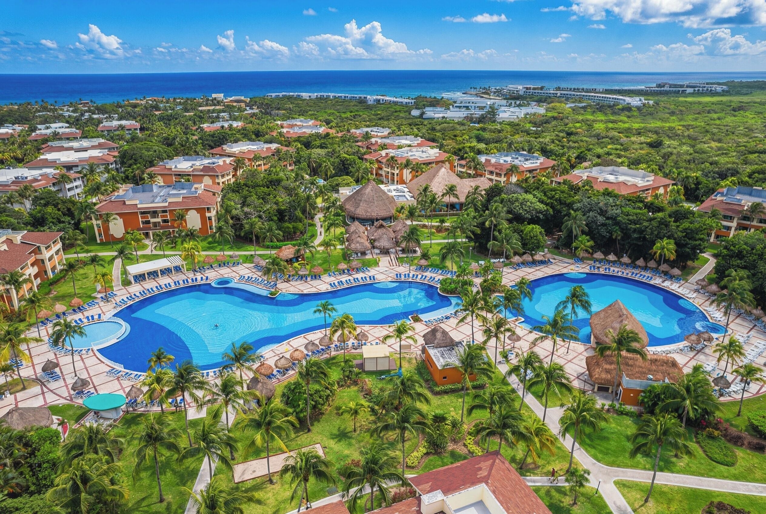 Ein Resort mit einem großen zentralen Pool, mehreren kleineren Pools und einem Strandbereich.