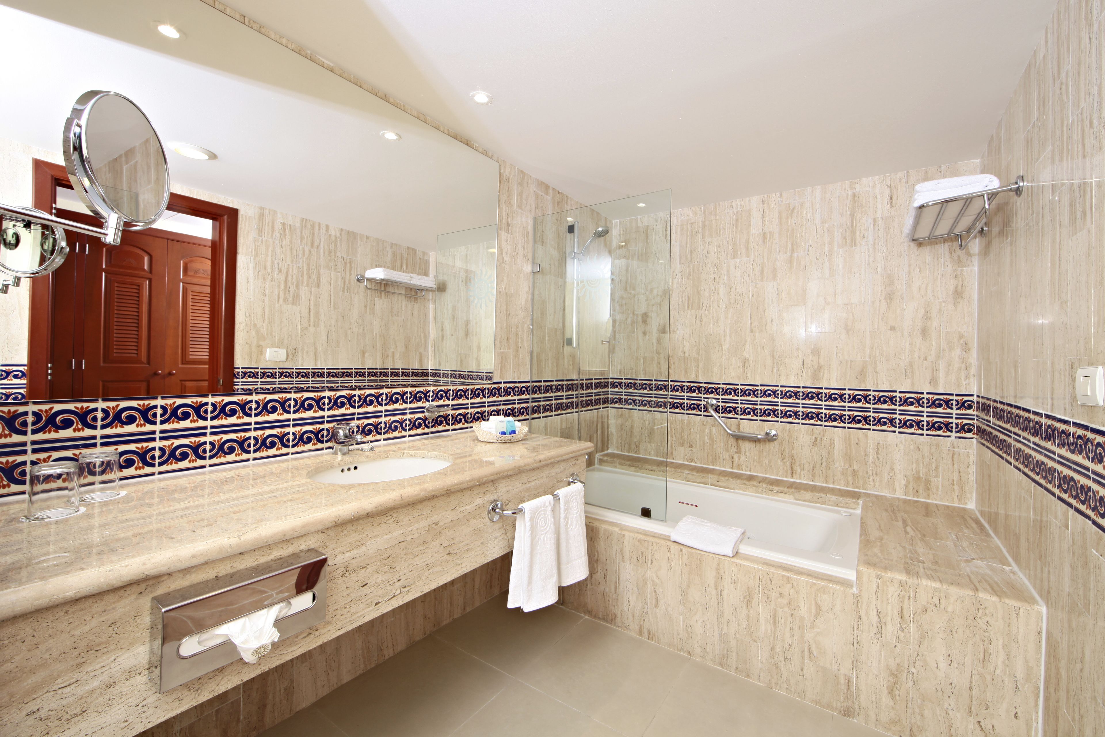 A modern bathroom with a large mirror, two sinks, a bathtub, and a glass-enclosed shower.
