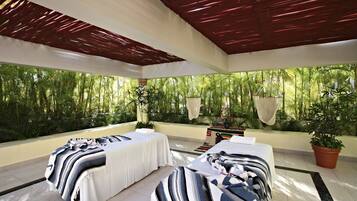 Relax in a serene spa area with two massage tables, lush greenery, and a natural ambiance.