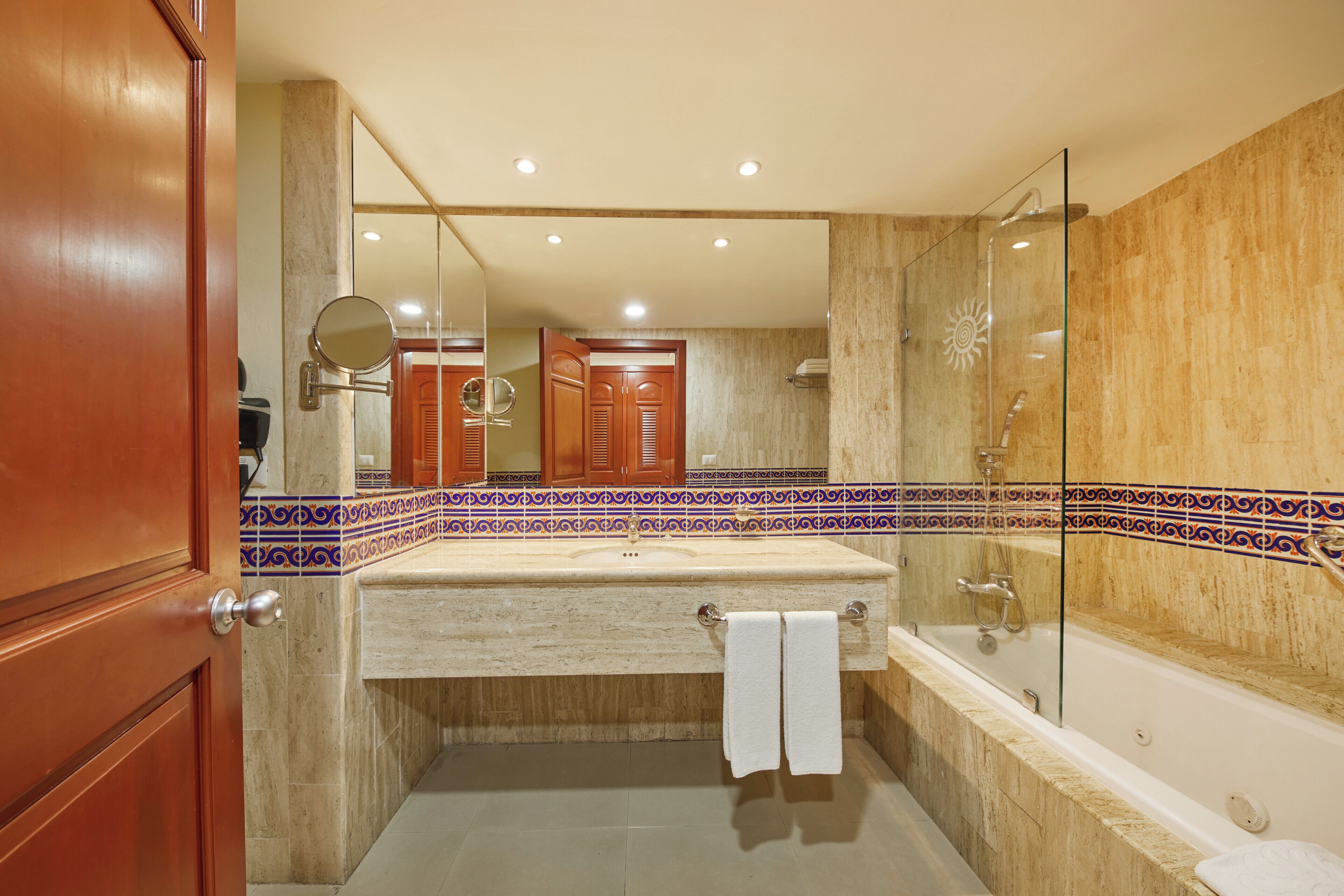 A bathroom with a marble sink, a glass-enclosed shower, and a wooden door.