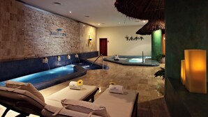Un espace spa agrémenté d’un mur en pierre, d’un bain à remous et de chaises longues avec des serviettes à disposition.