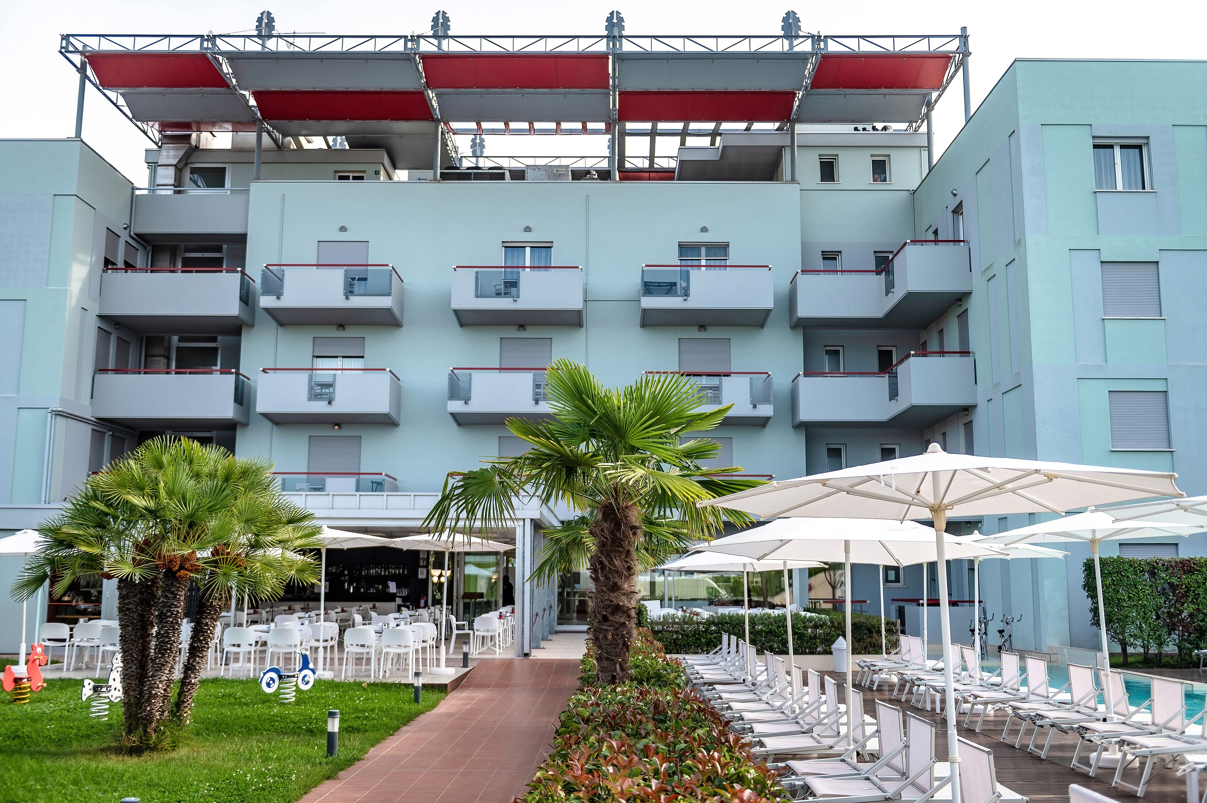 A hotel with multiple balconies, outdoor seating, and a swimming pool.