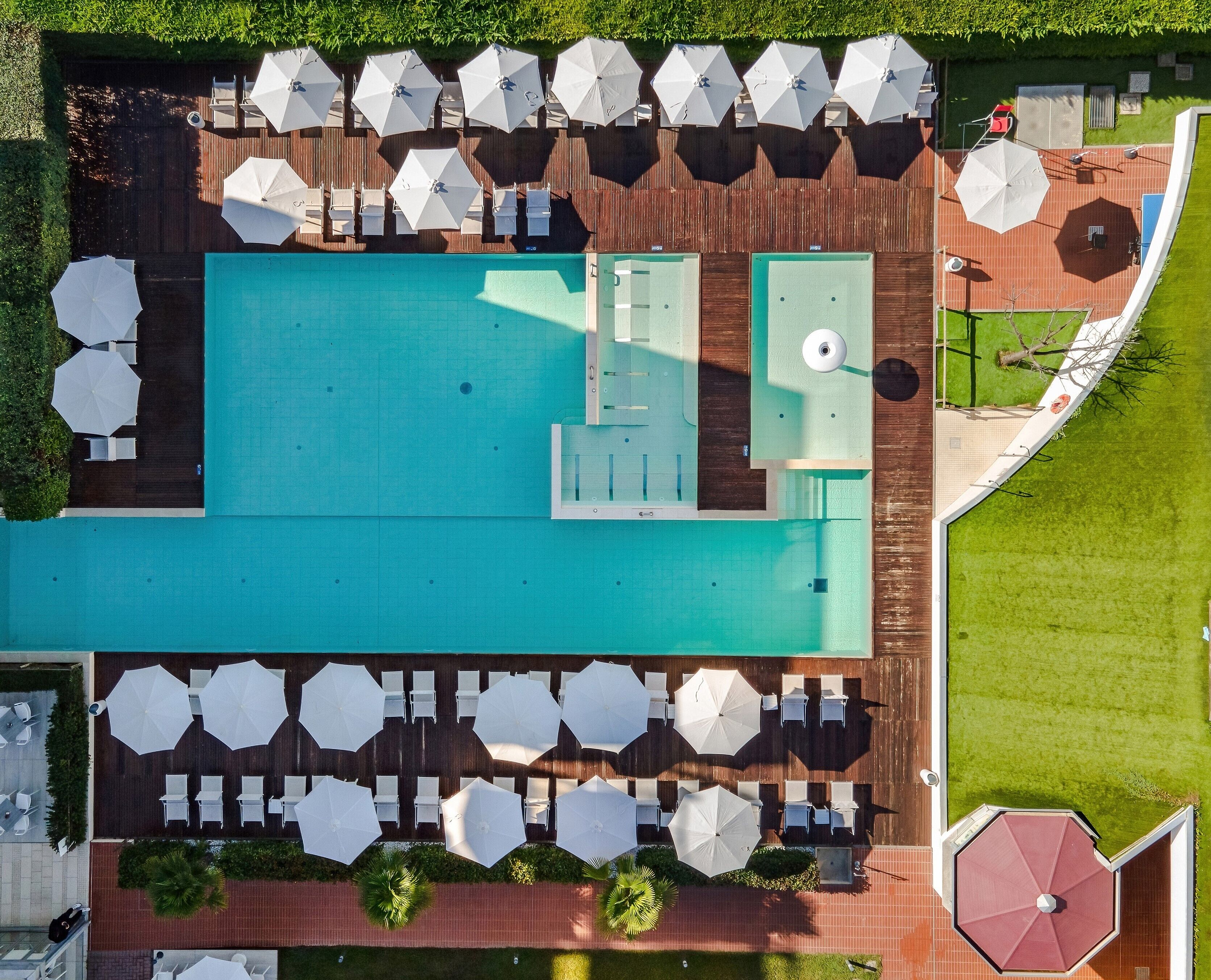 An aerial view of a pool area with multiple seating arrangements and umbrellas.