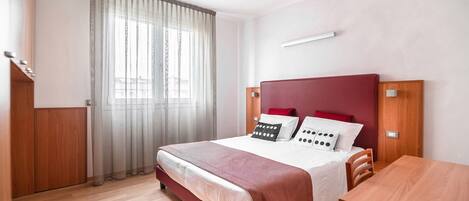 A modern hotel room with a large bed, wooden headboard, and a wooden table.