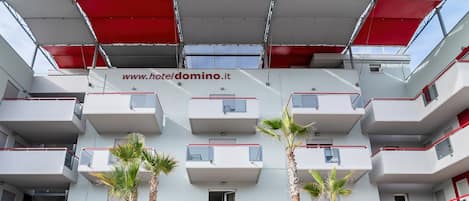 Un edificio moderno con varios balcones y una dirección web visible.