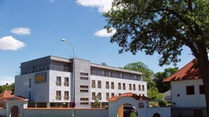 Ein mehrstöckiges Gebäude mit weißer Fassade und roten Ziegeln auf dem Dach.