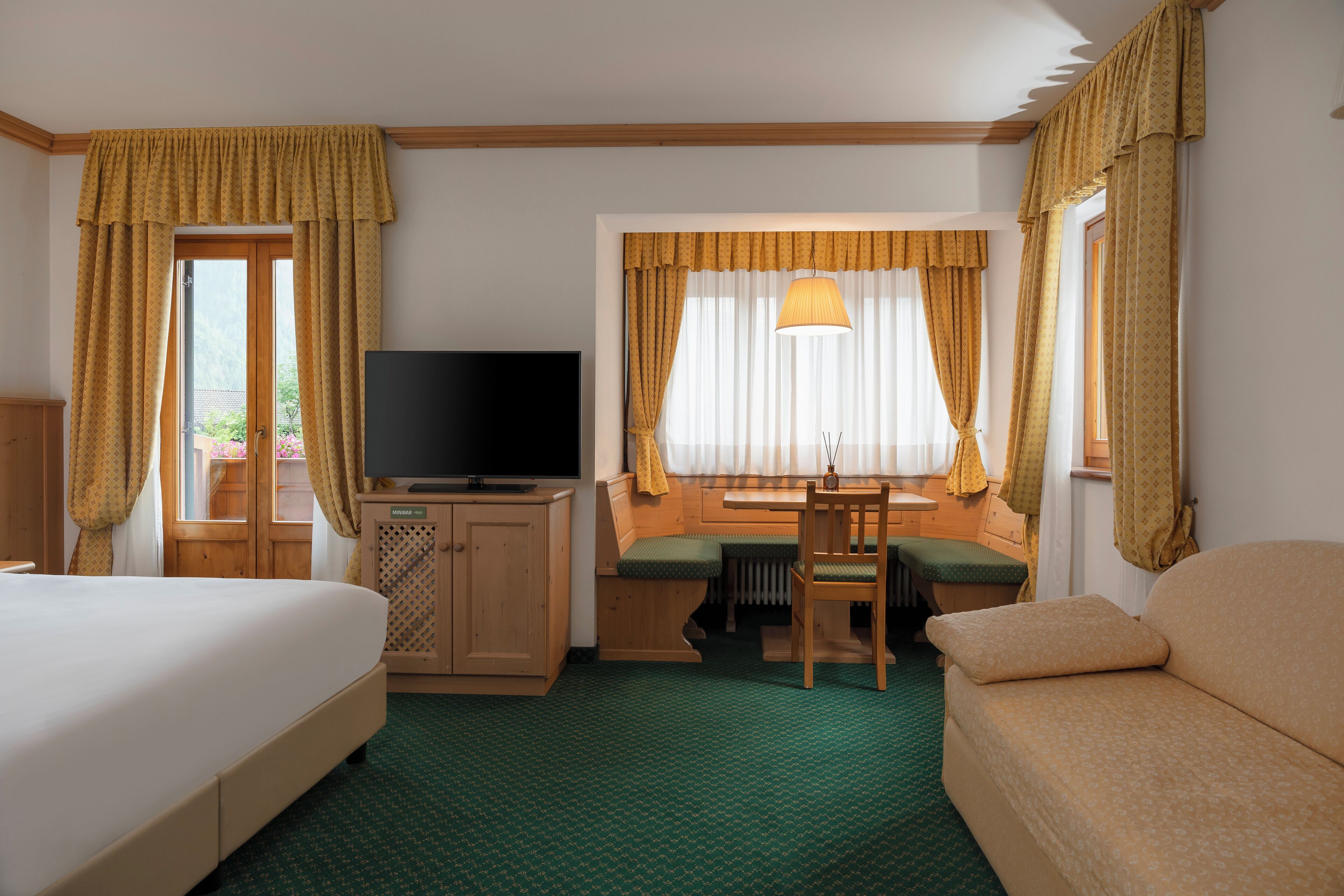 Habitación de hotel con cama, escritorio con silla, televisor y sofá.