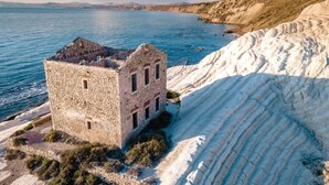 An ancient stone building with a rugged coastline in the background.
