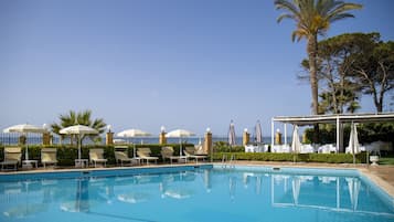 Una piscina al aire libre, sombrillas, sillones reclinables de piscina