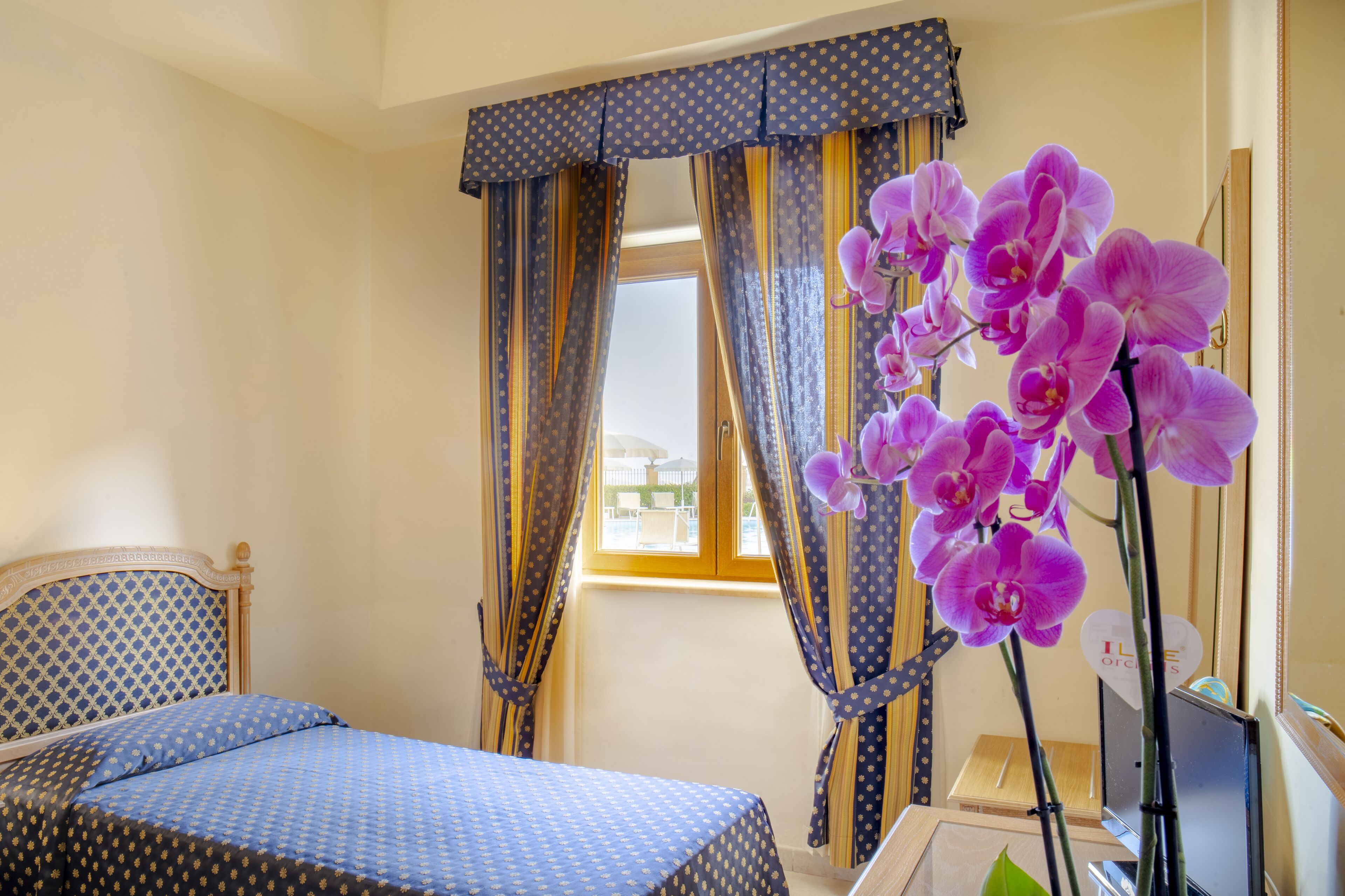 Une chambre à coucher avec un lit, des rideaux et une plante orchidée.