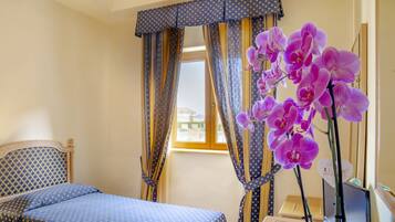 Une chambre à coucher avec un lit, des rideaux et une plante orchidée.
