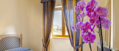 Une chambre à coucher avec un lit, des rideaux et une plante orchidée.