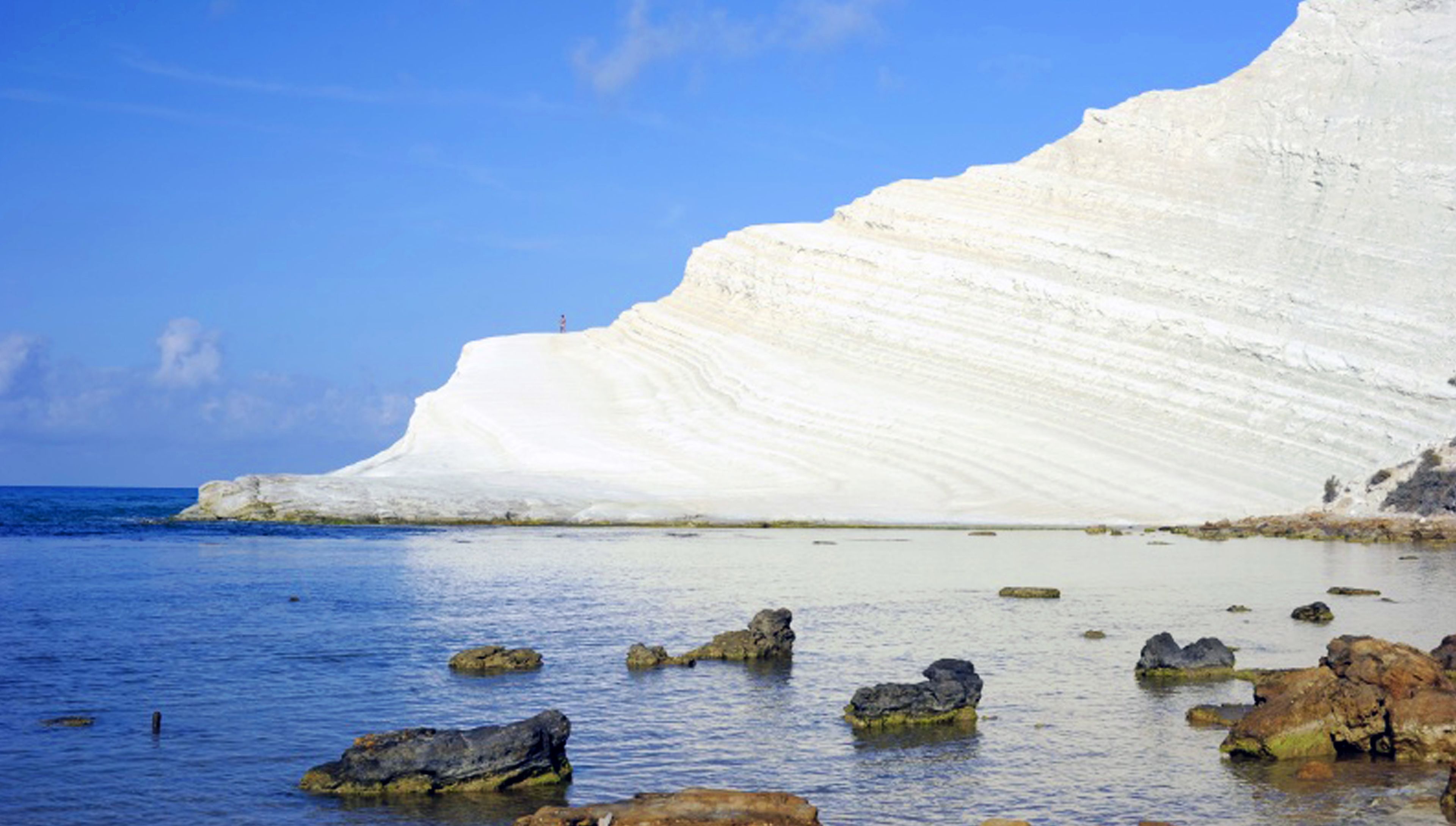 A coastal landscape with white cliffs and calm sea.