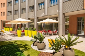 An outdoor seating area with tables, chairs, and umbrellas.