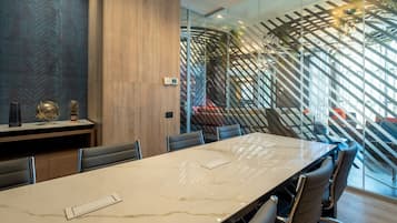 A modern conference room with a large marble table, leather chairs, and a glass partition with a geometric pattern.