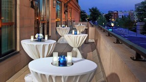 Een terras op het dak met daar tafels voor dineren, een Amerikaanse vlag en een uitzicht over de stad.