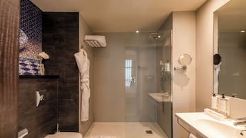 Une salle de bain moderne avec une douche à parois de verre, des toilettes blanches et un meuble-lavabo avec un miroir.