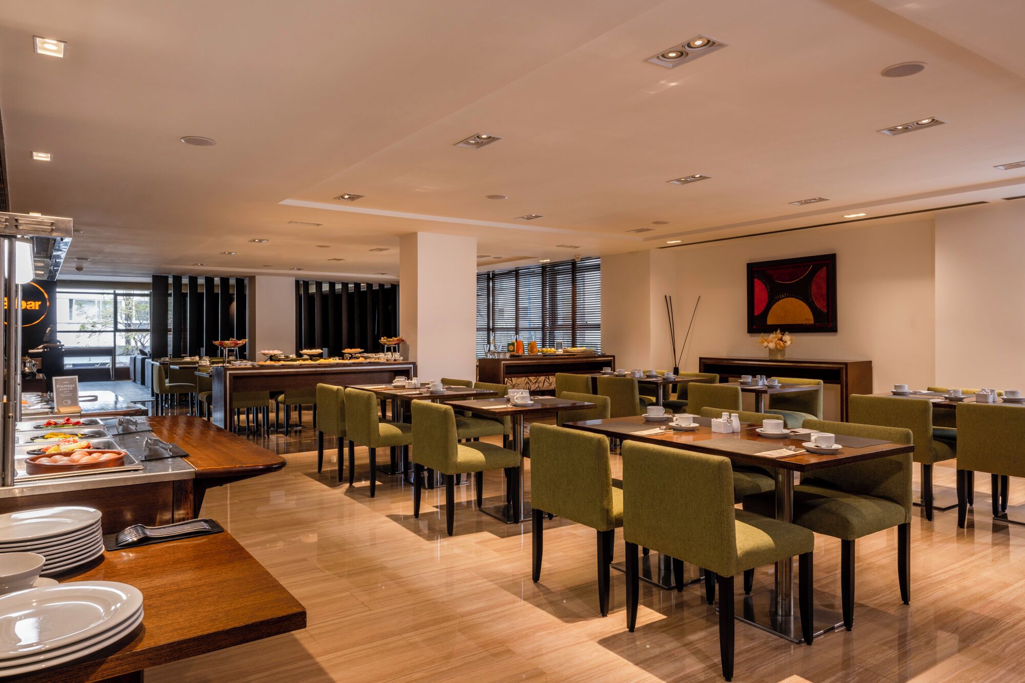 A modern dining area with multiple tables and chairs, a buffet with various food items, and a large window providing natural light.