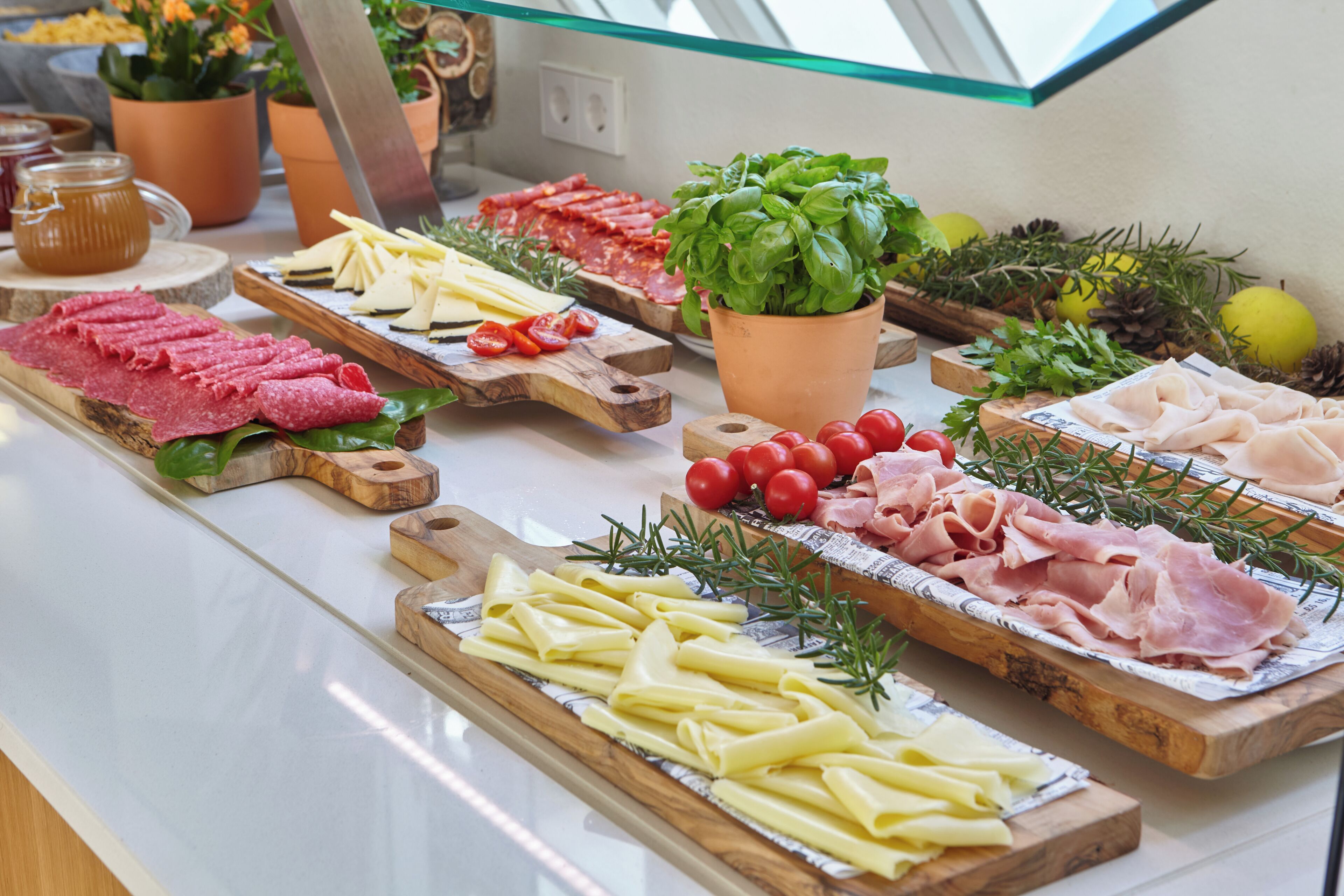 Diversos alimentos expuestos en tablas de madera, como carnes, quesos y verduras.